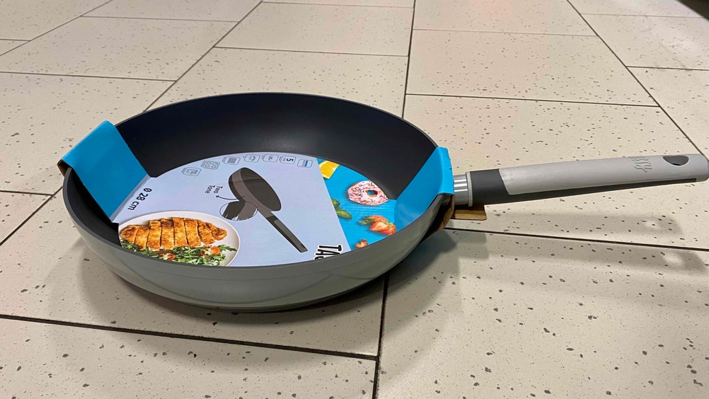 Wokpfanne im Test: Wokpfanne steht auf einem Fliesenboden mit schwarz-grauem Griff.