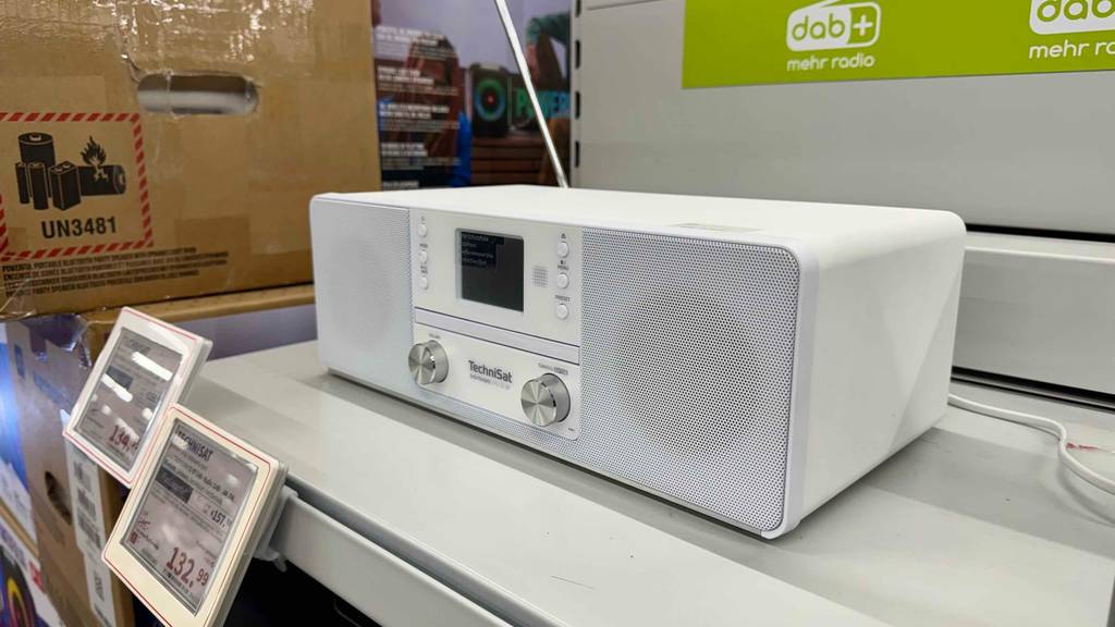 Ein weißer getesteter Radiowecker mit CD-Player steht in einem Verkaufsbereich.