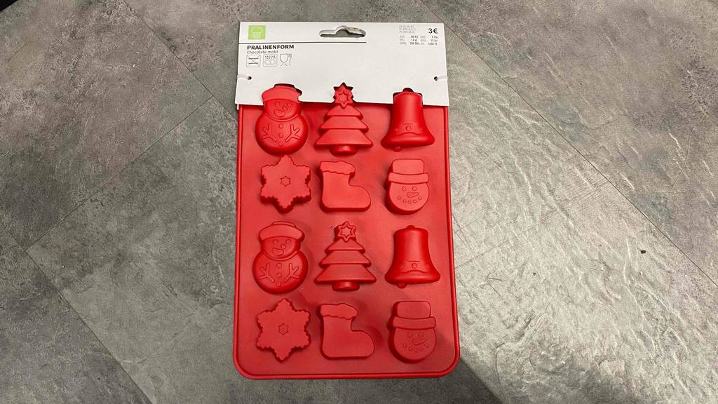 Pralinenformen-Test: Auf einem dunklen Boden liegt eine rote Pralinenform mit weihnachtlichen Motiven.
