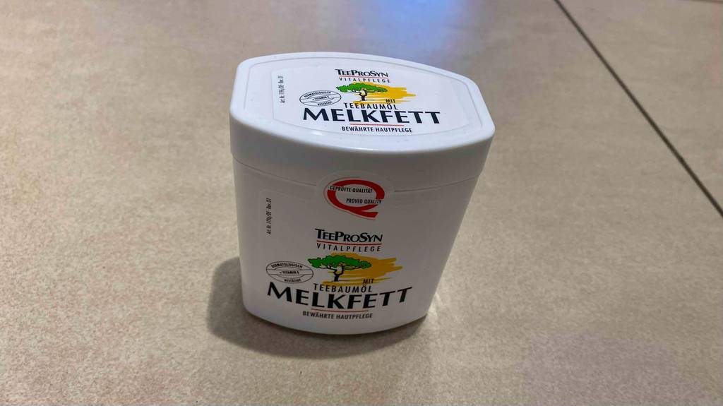 Melkfett im Test: Melkfett mit Teebaumöl steht auf einem Fliesenboden.