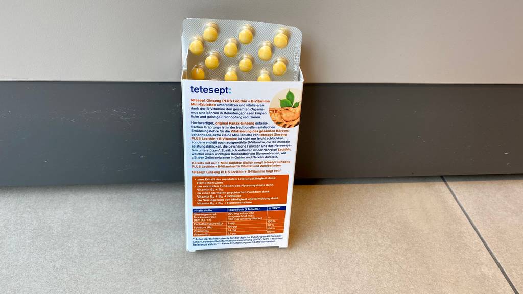 Ginseng-Kapseln im Test: Aus einer Packung Kapseln schaut ein Tablettenblister heraus, die Packung steht vor einer Wand