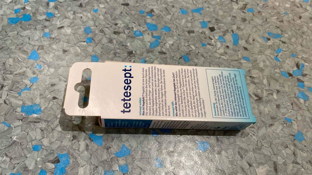 Im Test: Eine Packung Mittel gegen Nagelpilz liegt mit der Rückseite nach oben auf einem Boden.