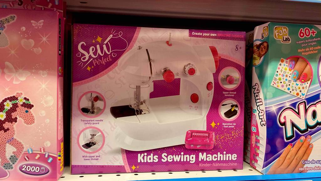 Im Test: Eine verpackte Kindernähmaschine steht neben anderen Produkten im Regal.