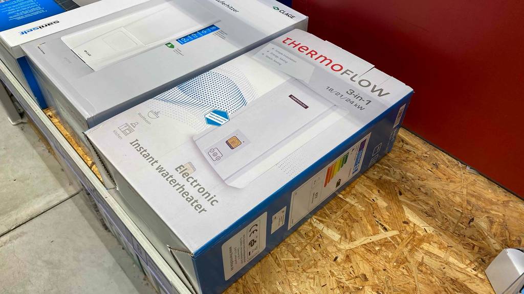 ThermoFlow Durchlauferhitzer getestet: Ein verpacktes Gerät liegt neben anderen auf einer Holzfläche.
