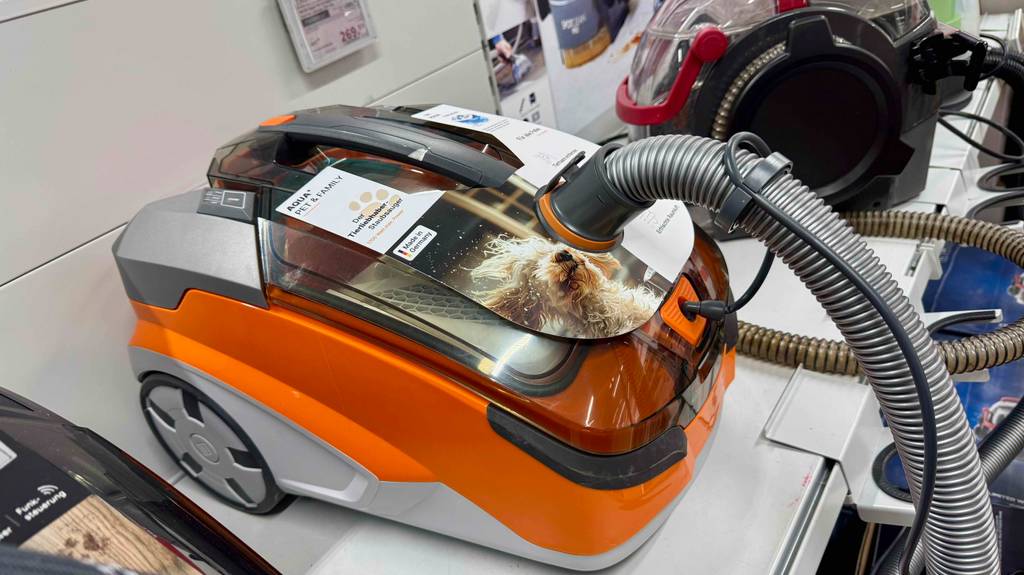 Im Test: Der Thomas-Staubsauger in Weiß-orange steht auf einem Ausstellungsregal neben weiteren Staubsaugern.