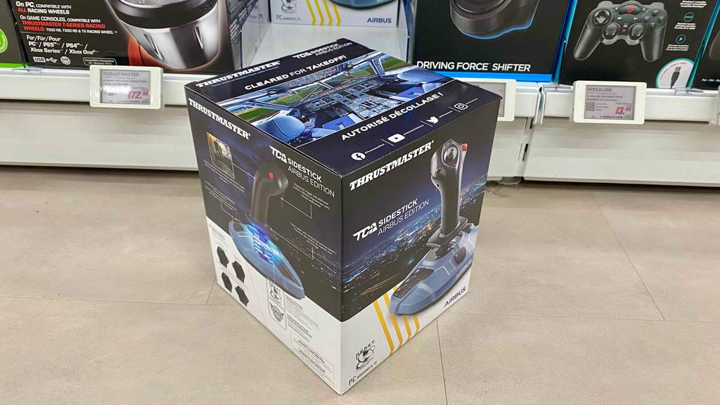 Joystick im Test: Verpackung von Joystick vor einem Regal stehend.