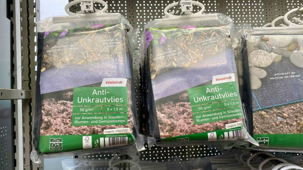 Unkrautvlies-Test: Mehrere Packungen Unkrautvlies hängend in einem Regal mit Preisschild ersichtlicih.