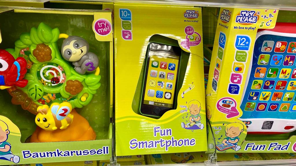 Smartphone-für-Kinder getestet: Kindersmartphone in einer Verpackung steht in einem Regal neben anderem Spielzeug für Kinder.