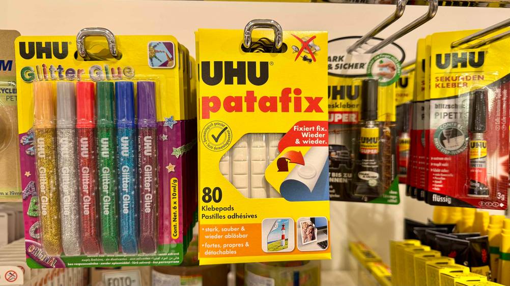 Die getesteten Klebepads hängen in einem Regal neben Glitzerstiften.