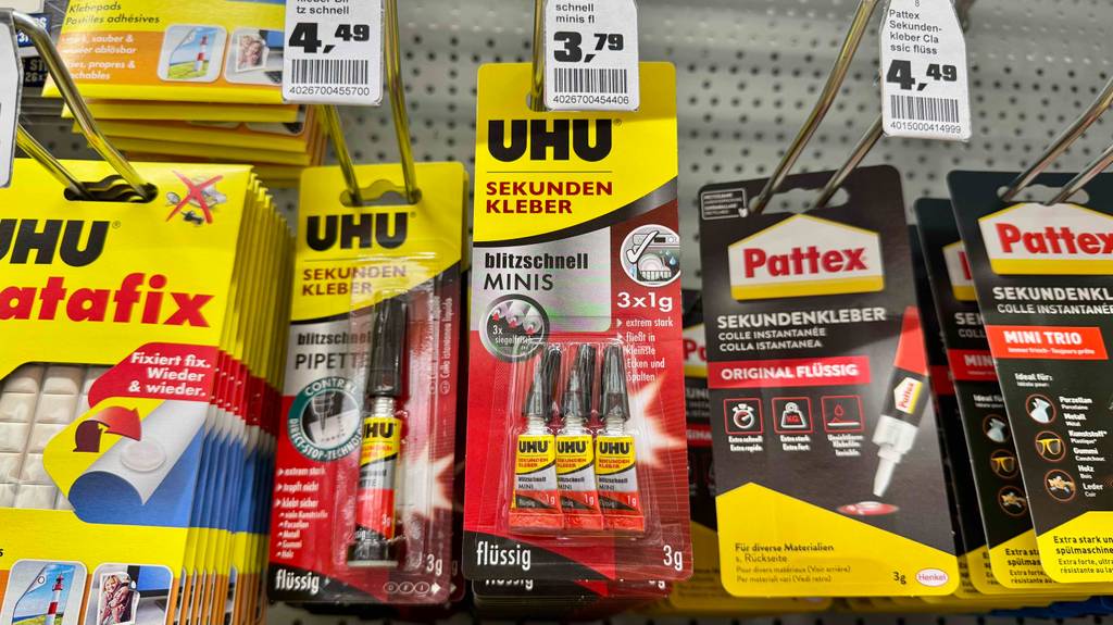 Getesteter UHU-Kleber hängt in einem Regal neben anderen Artikeln.