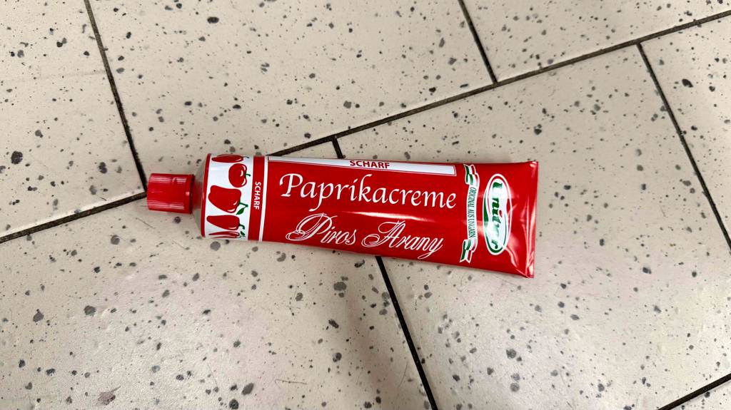 Eine getestete Tube Paprikapaste liegt auf einem Boden.