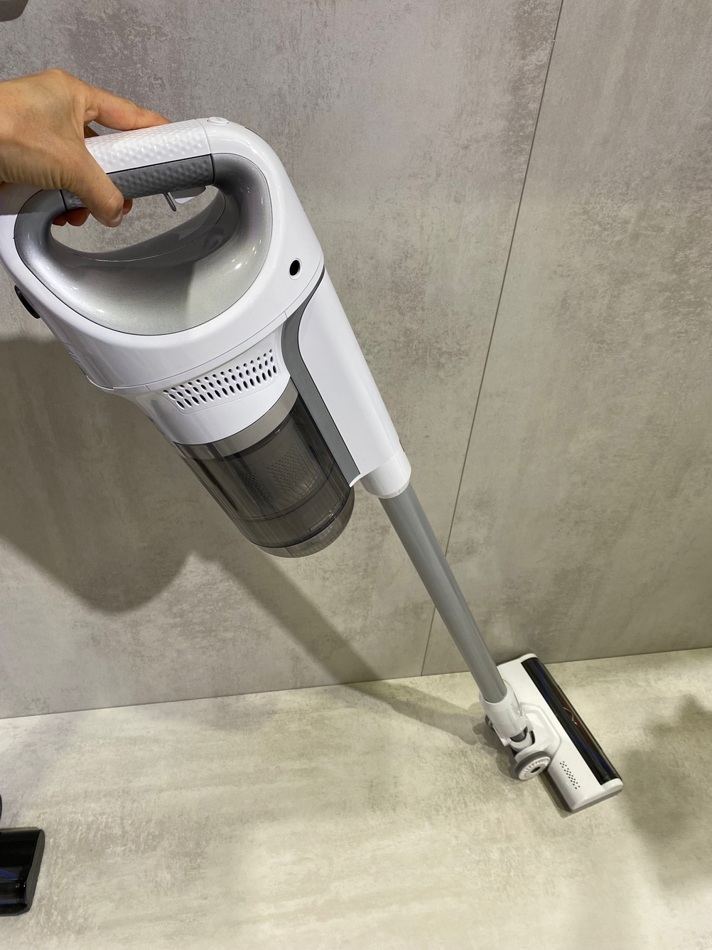 Eine Hand bewegt einen getesteten Standstaubsauger über eine helle Fläche.