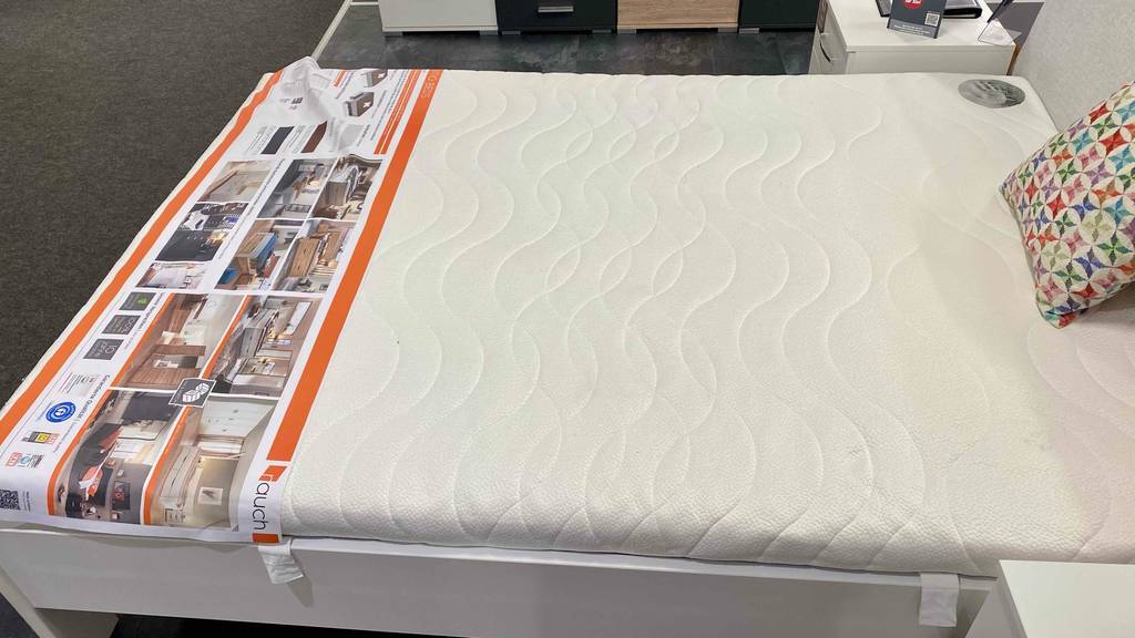 Matratze-140x220 im Test: eine Matratze liegend auf einem Bett in einem Geschäft.