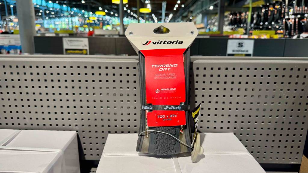 Der getestete Faltreifen in der roten Verpackung steht auf einem weißen Karton im Geschäft.