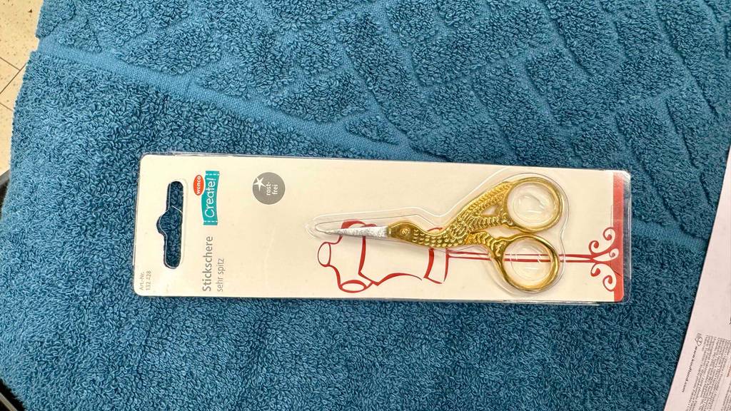 Eine getestete Stickschere liegt auf einem blauen Handtuch.