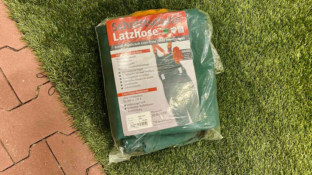 Schnittschutzhose getestet: eine Schnittschutzhose in einer Plastikverpackung liegend auf einem Raasenteppich.