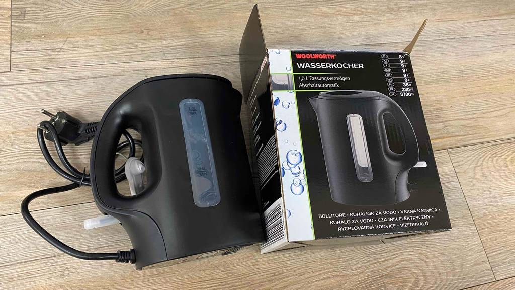 Wasserkocher 1 Liter getestet: Ein Produkt liegt neben seiner Verpackung auf einem Holzboden.