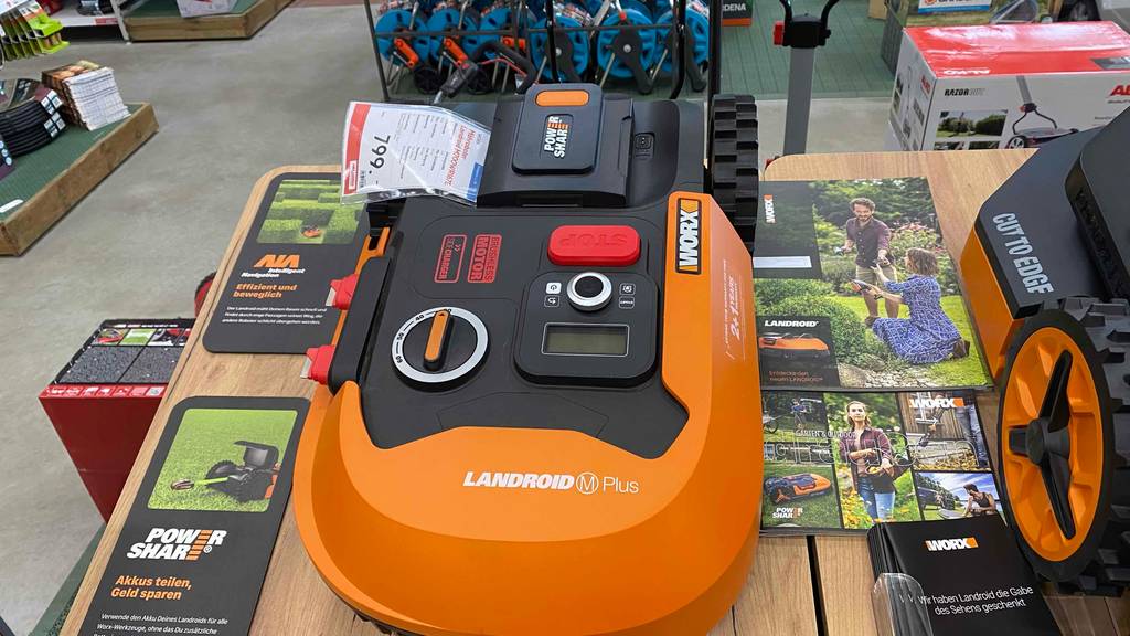 Worx-Mähroboter getestet: orangefarbiger Worx-Mähroboter steht als Ausstellungsstück in einem Geschäft.