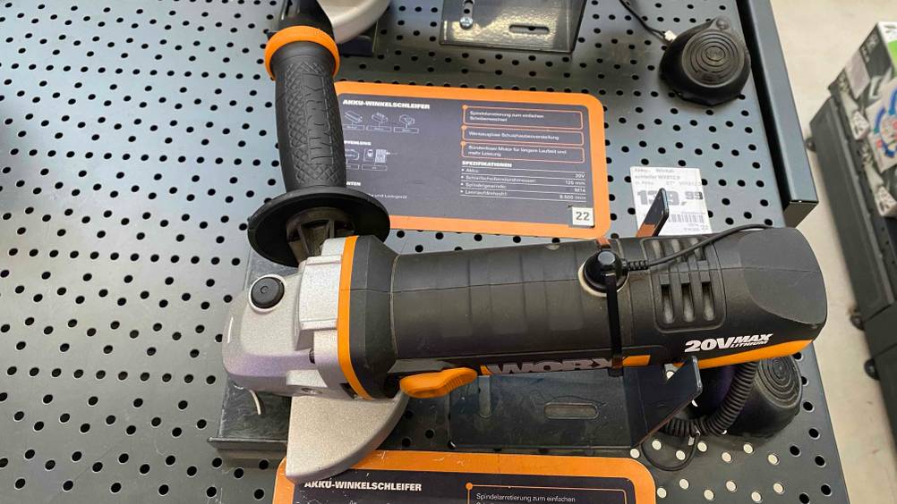 Winkelschleifer-115-mm im Test: Winkelschleifer der Marke Worx wird in einem Geschäft ausgestellt, mit Preisschild und Informationstafel zum Produkt.