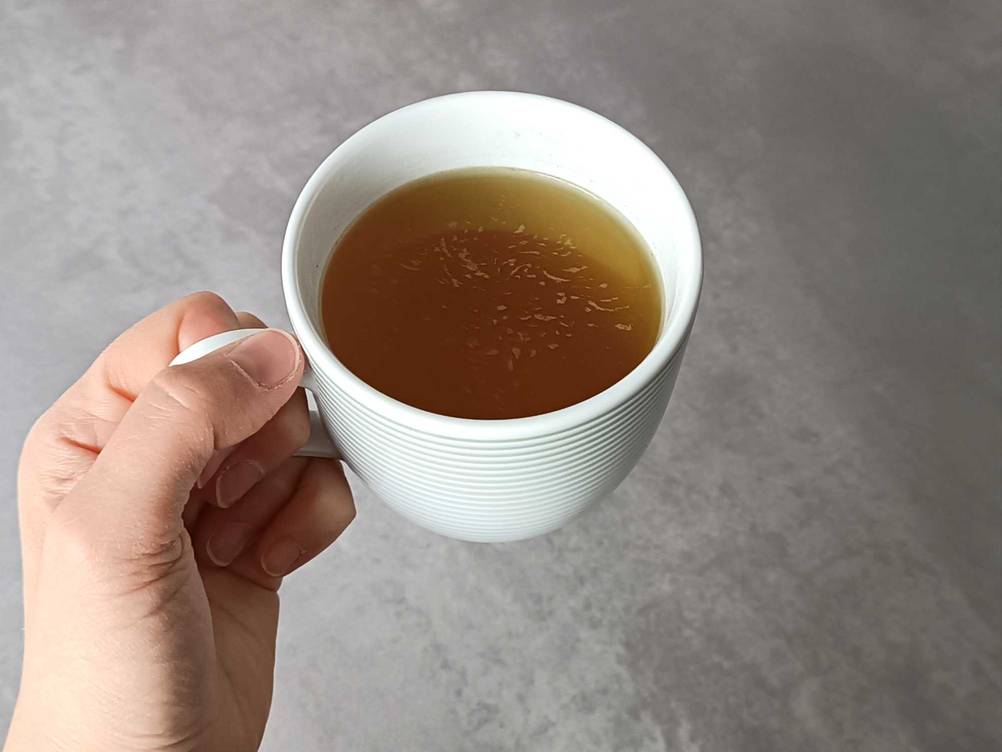 Im Test: Eine Hand hält Kräutertee in einer Tasse.
