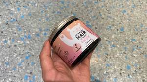 Haar-Vitamine getestet: Eine Hand hält eine Packung vor einen grauen Hintergrund