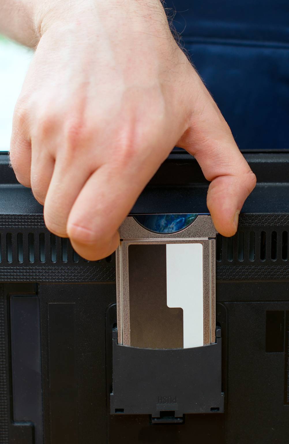 Hand steckt eine Smartcard in ein Cl+-Modul.
