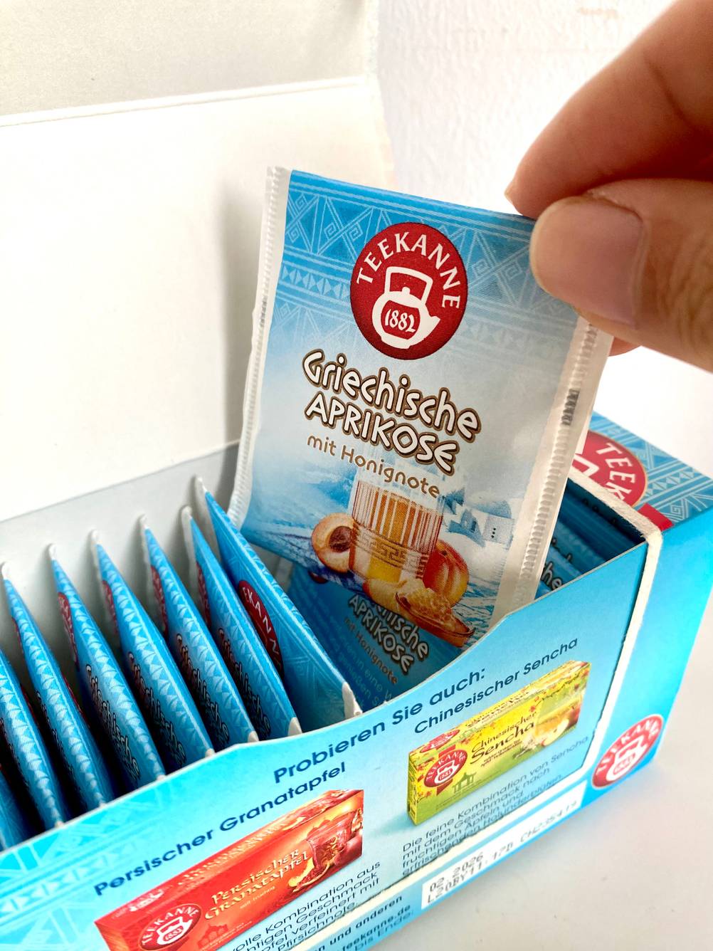 Früchtetee wird aus Schachtel herausgenommen.