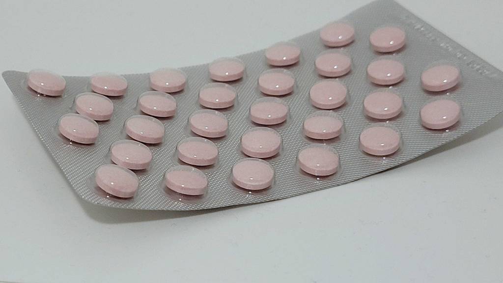 Blisterverpackung mit Tabletten darin von getesteten Vitamin-B12 liegend auf einer weißen Fläche.