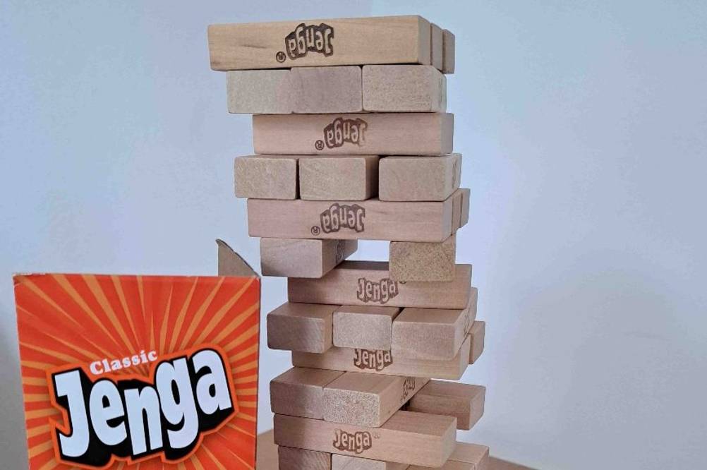 Spiele ab 6 Jahren getestet: Ein auf gebauter Holzklotzstapel neben der Spieleverpackung.
