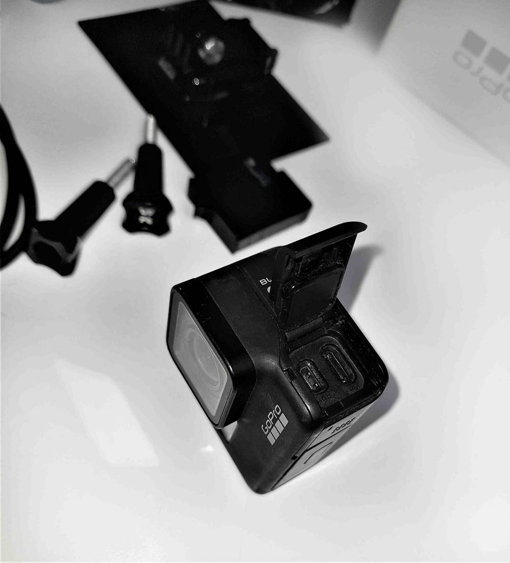 Ein 4k-Camcorder im Test mit geöffneter Schutzkappe für Anschlüsse auf einer hellen Fläche im Hintergrund Zubehör.