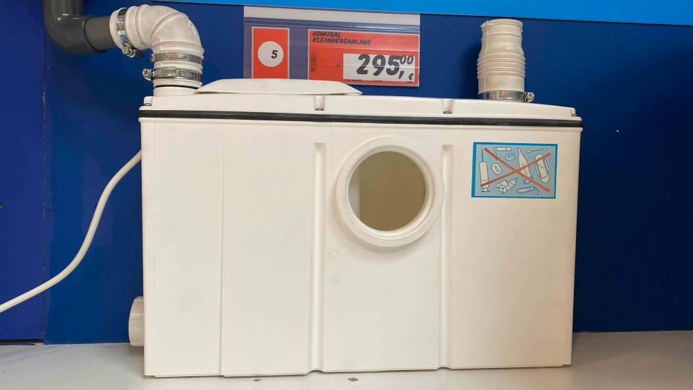 Vor einer blauen Wand steht eine getestete Hebeanlage auf einem hellen Untergrund.