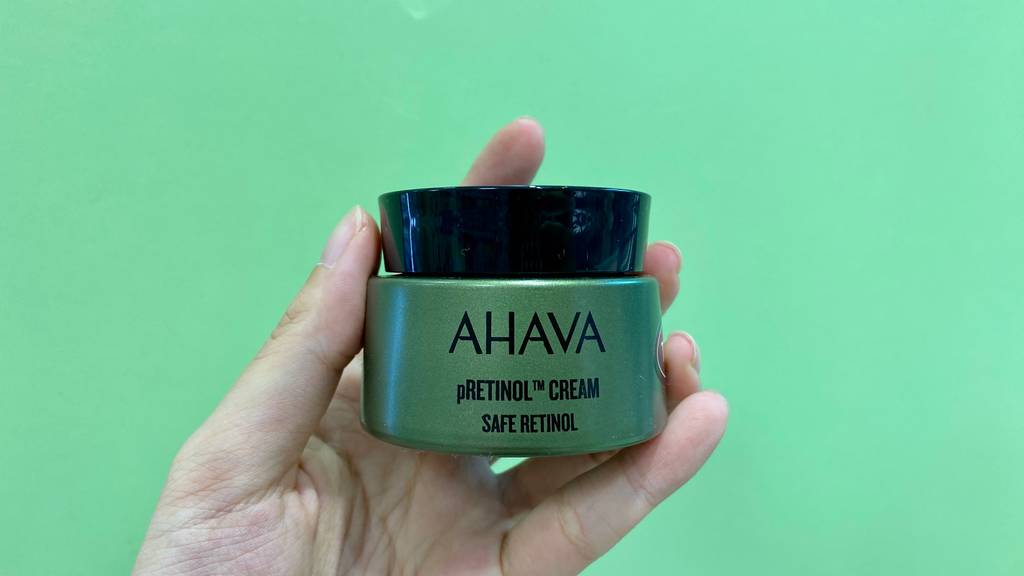 Retinol-Creme getestet: Geschlossene Creme wird vor grünem Hintergrund gehalten.