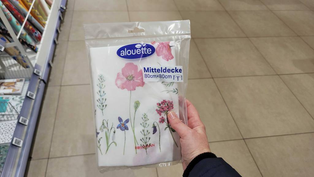 Die getestete Papiertischdecke wird in der transparenten Verpackung in der Hand gehalten.