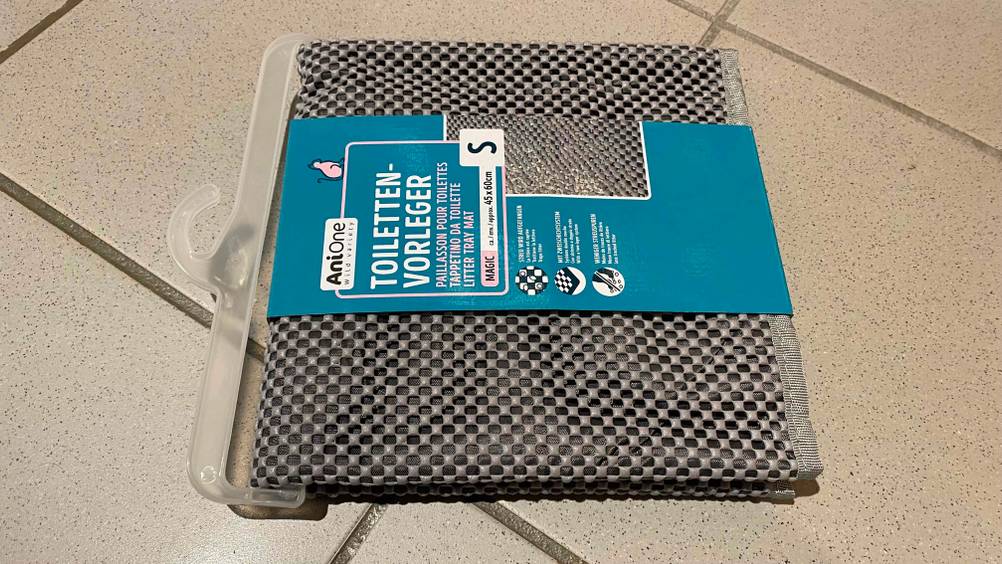 Katzenstreu-Matte getestet: Eine verpackte Katzenstreu-Matte liegt horizontal auf einem Fließenboden