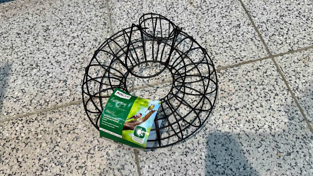 Ein Meisenknödelhalter, der getestet wurde, liegt auf einem Boden.