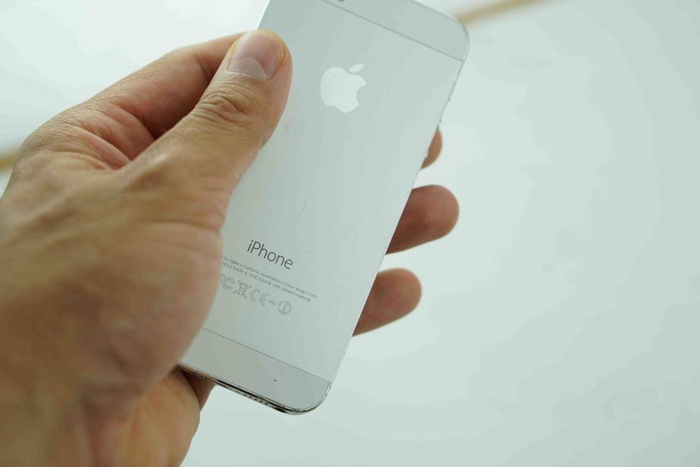 Smartphones bis 200 Euro im Test: Eine Hand hält ein Gerät mit der Rückseite nach vorne vor eine helle Wand