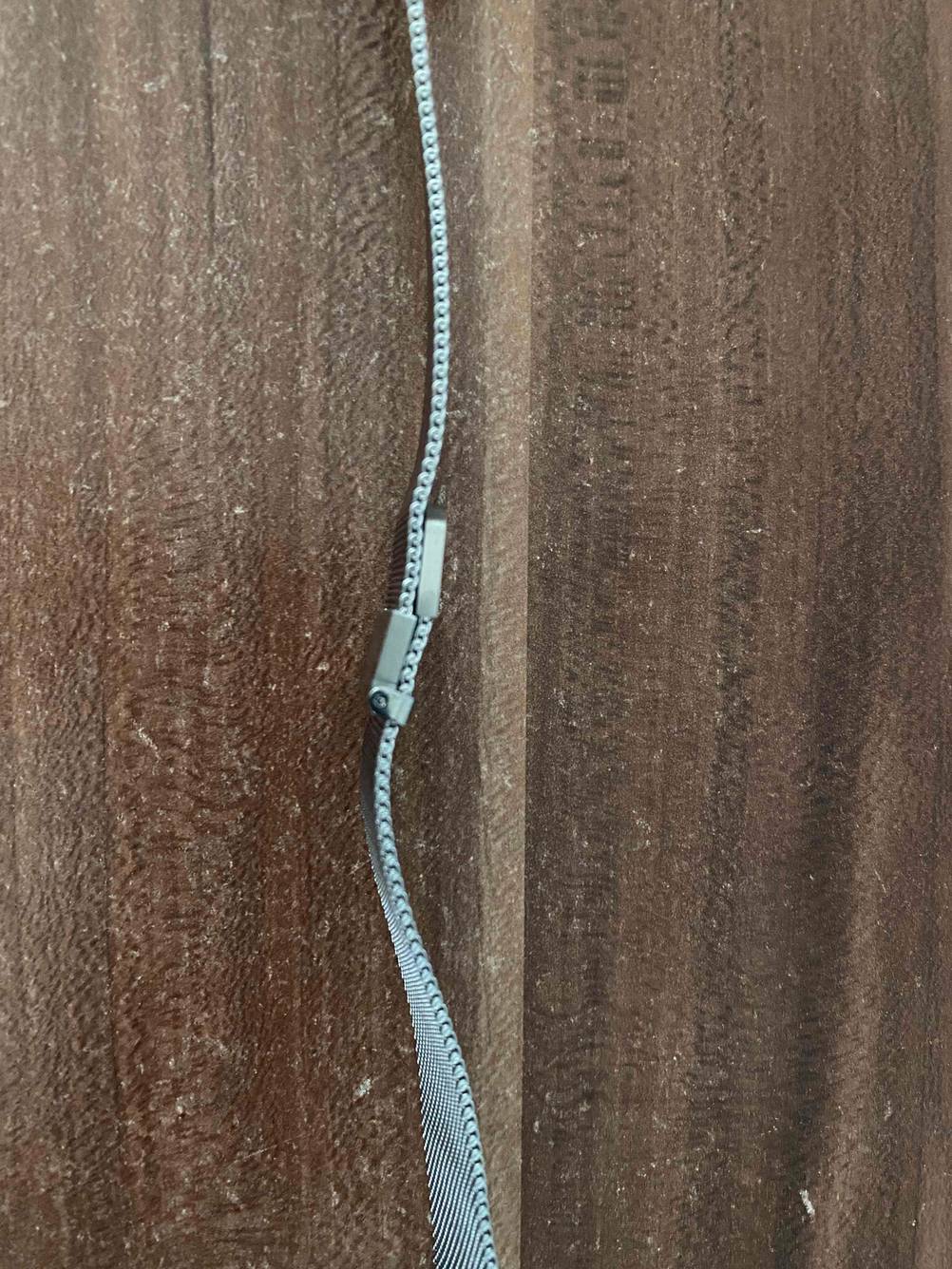 Verschluss eines getesteten Apple-Watch-Armbands von der Seite auf einem Holztisch.