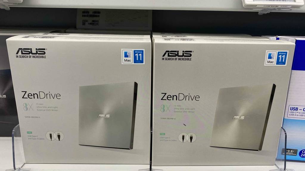 Im Test: Ein verpackter DVD-Brenner von asus neben anderen in einem Regal.