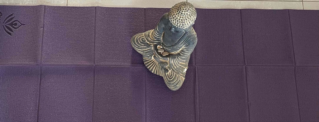Reise-Yogamatte getestet: Eine Buddha-Figur sitzt auf einer lila Matte.