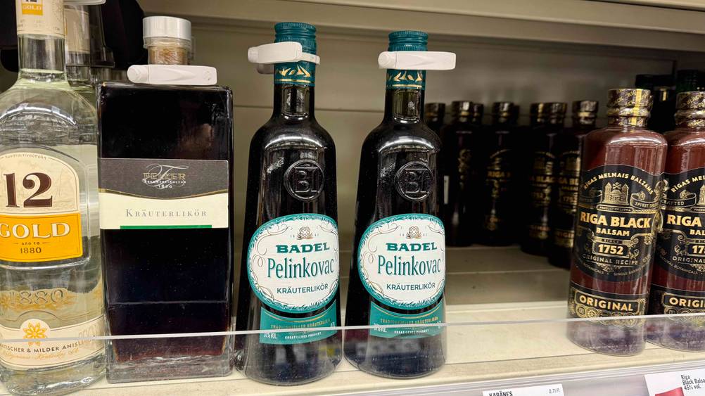 Zwei Flaschen des getesteten Pelinkovac stehen in einem Regal neben anderen alkoholischen Getränken.