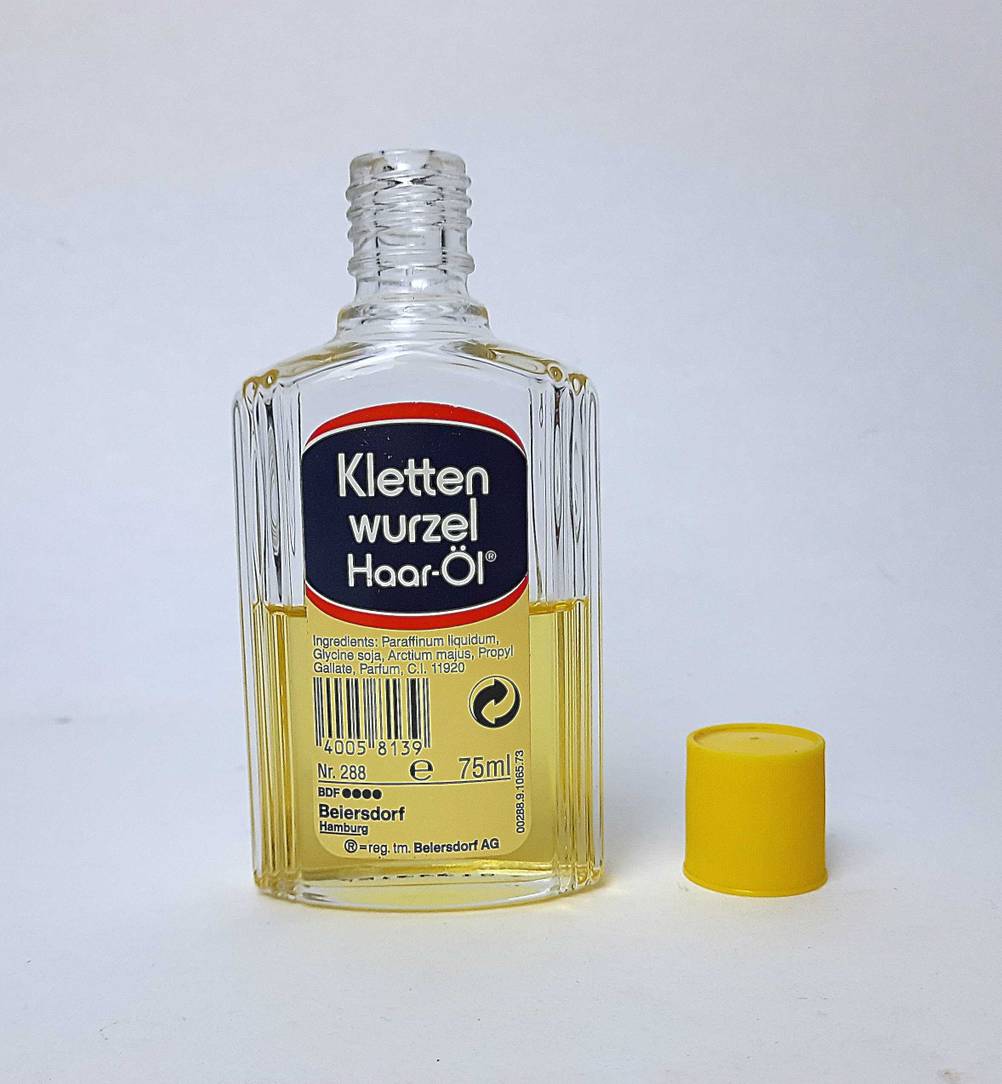 Eine geöffnete Flasche des getesteten Klettenwurzelöl steht neben dem Verschluss.