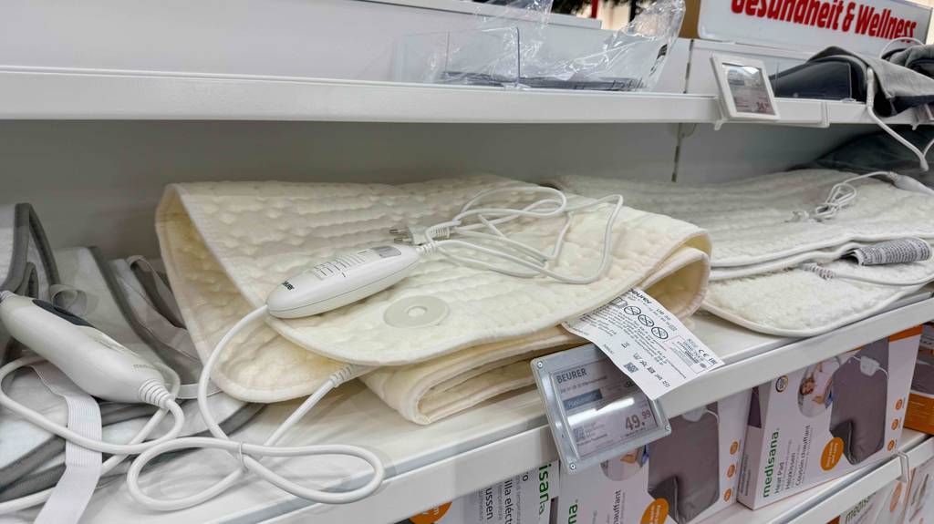 Auf einem weißen Regal befindet sich das beigefarbene Beurer-Wärmeunterbett im Test.