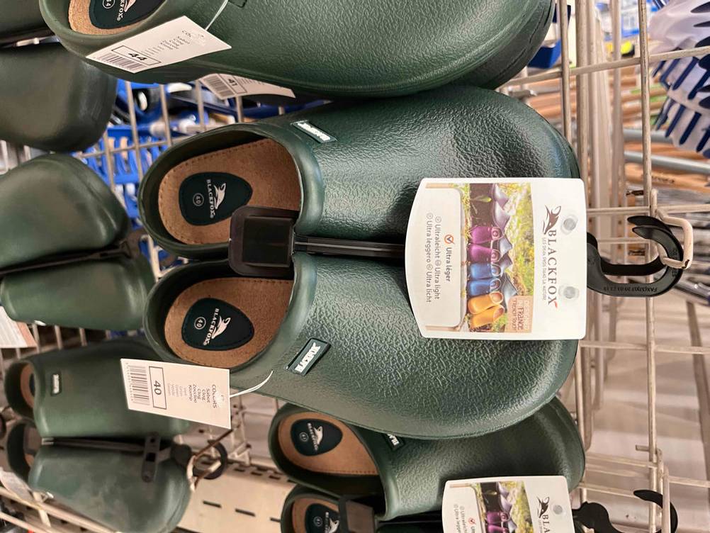 Gartenschuhe im Test: Mehrere Paare hängen an einem Gitter