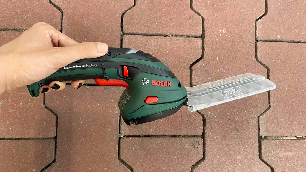 Akku-Grasschere wird im Test über einen Steinboden gehalten.