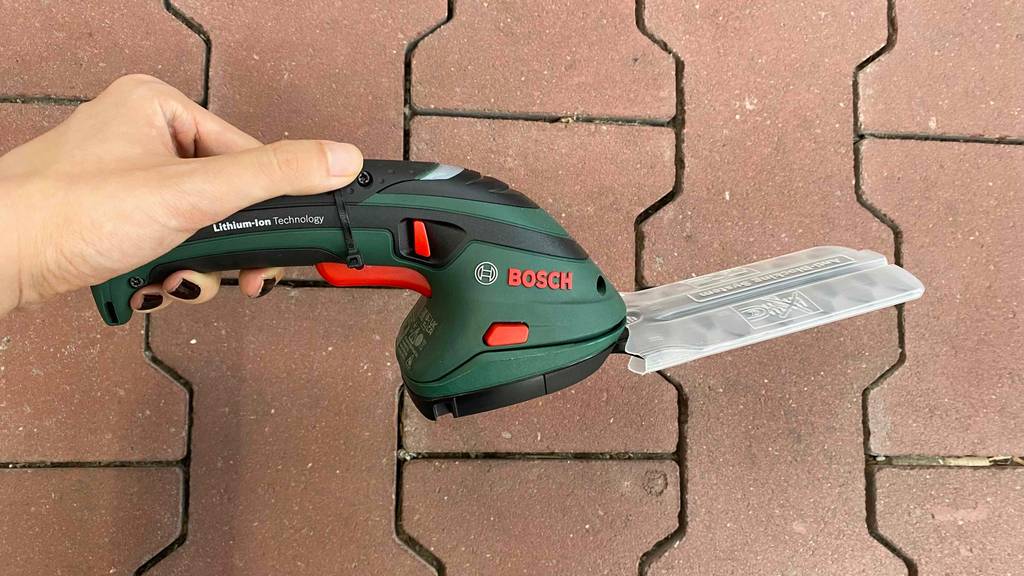 Akku-Grasschere wird im Test über einen Steinboden gehalten