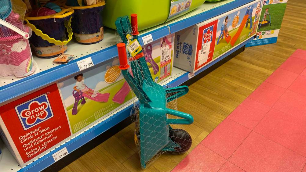 Eine getestete Kinderschubkarre von der Seite vor einem Regal stehend.