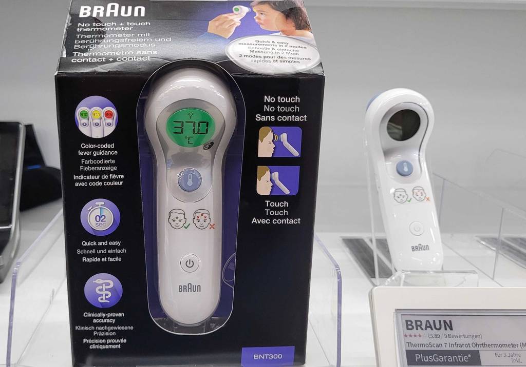 Die Verpackung des getesteten Stirnthermometers steht neben dem entsprechenden Gerät.