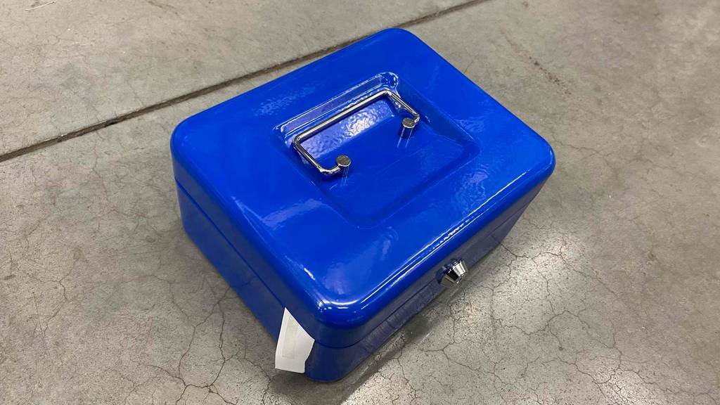 Im Test: Eine blaue Geldkassette von schräg oben auf einem grauen Boden.
