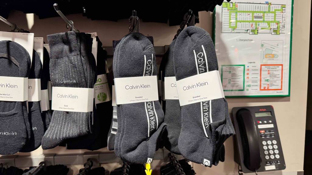 Mehrere Paar Herrensocken in Schwarz von Calvin Klein hängen in einem Regal.
