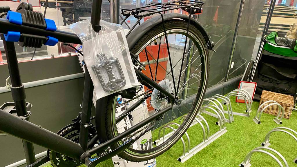 Trekkingrad getestet: Hinterrad eines Trekkingrads mit einem Pedal in einer Plastikverpackung an das Rad befestigt.